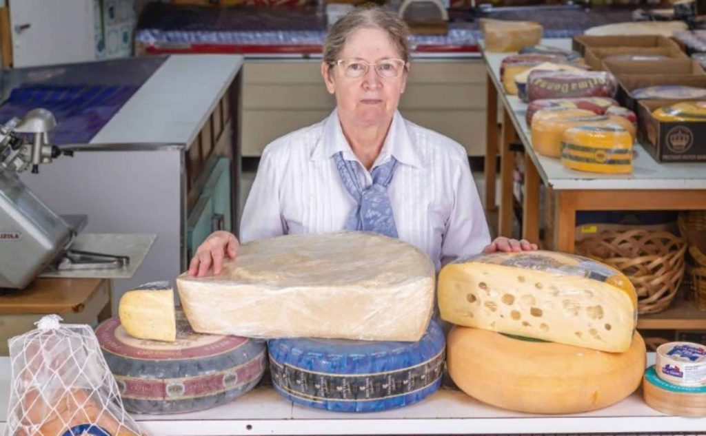 Entre os muitos tipos de queijos oferecidos na Mercearia Riograndense, dona Emi encontrou o seu lugar no mundo.| Foto: Rodrigo Pierrot/Prêmio Bom Gourmet Leia mais em: https://www.gazetadopovo.com.br/bomgourmet/entre-bries-e-gorgonzolas-uma-historia-de-dedicacao-no-comercio-de-queijos-em-curitiba/ Copyright © 2023, Gazeta do Povo. Todos os direitos reservados.